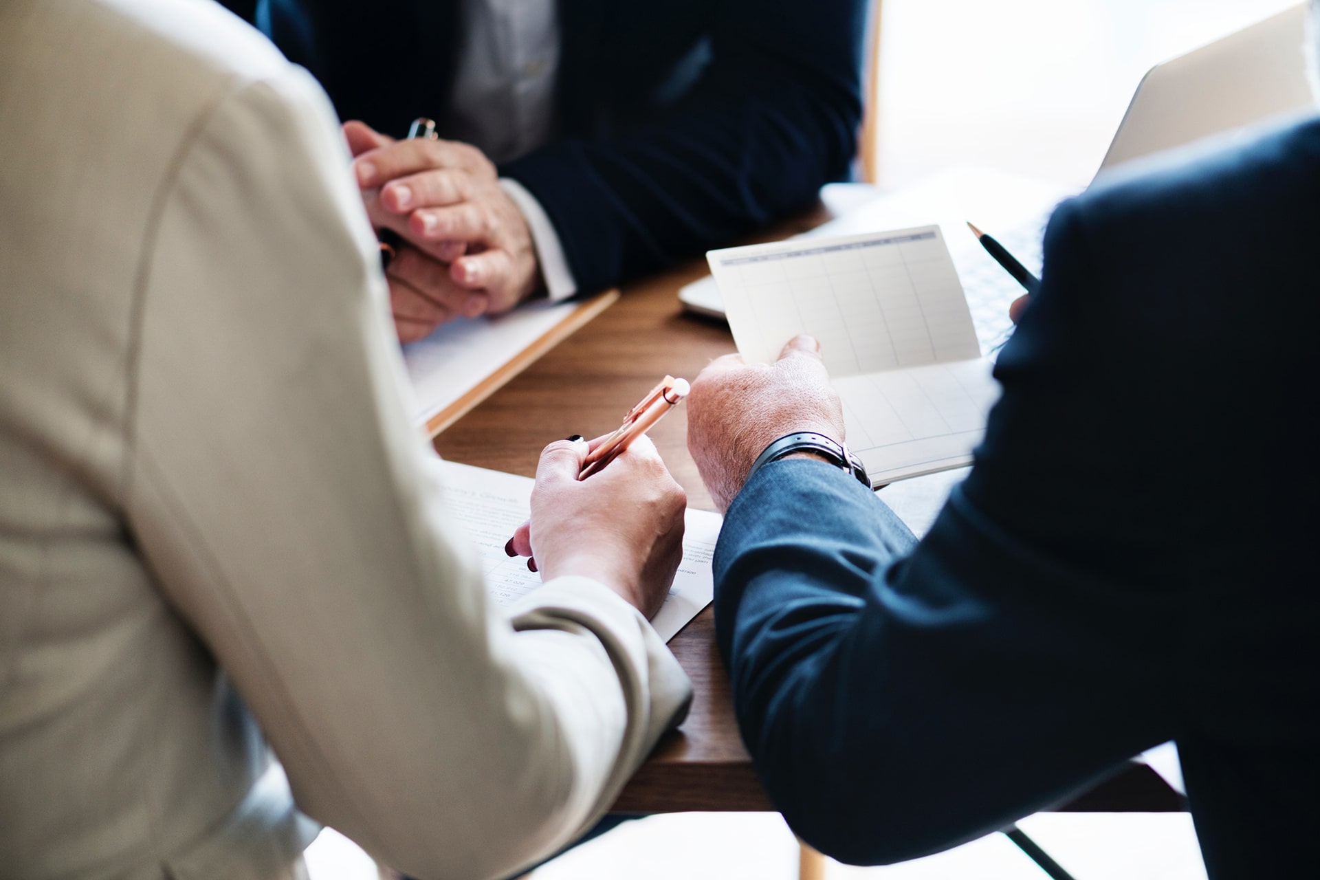 Torts Compensation Services legal consultation showing handshake between lawyer and client over documents with laptop and pen