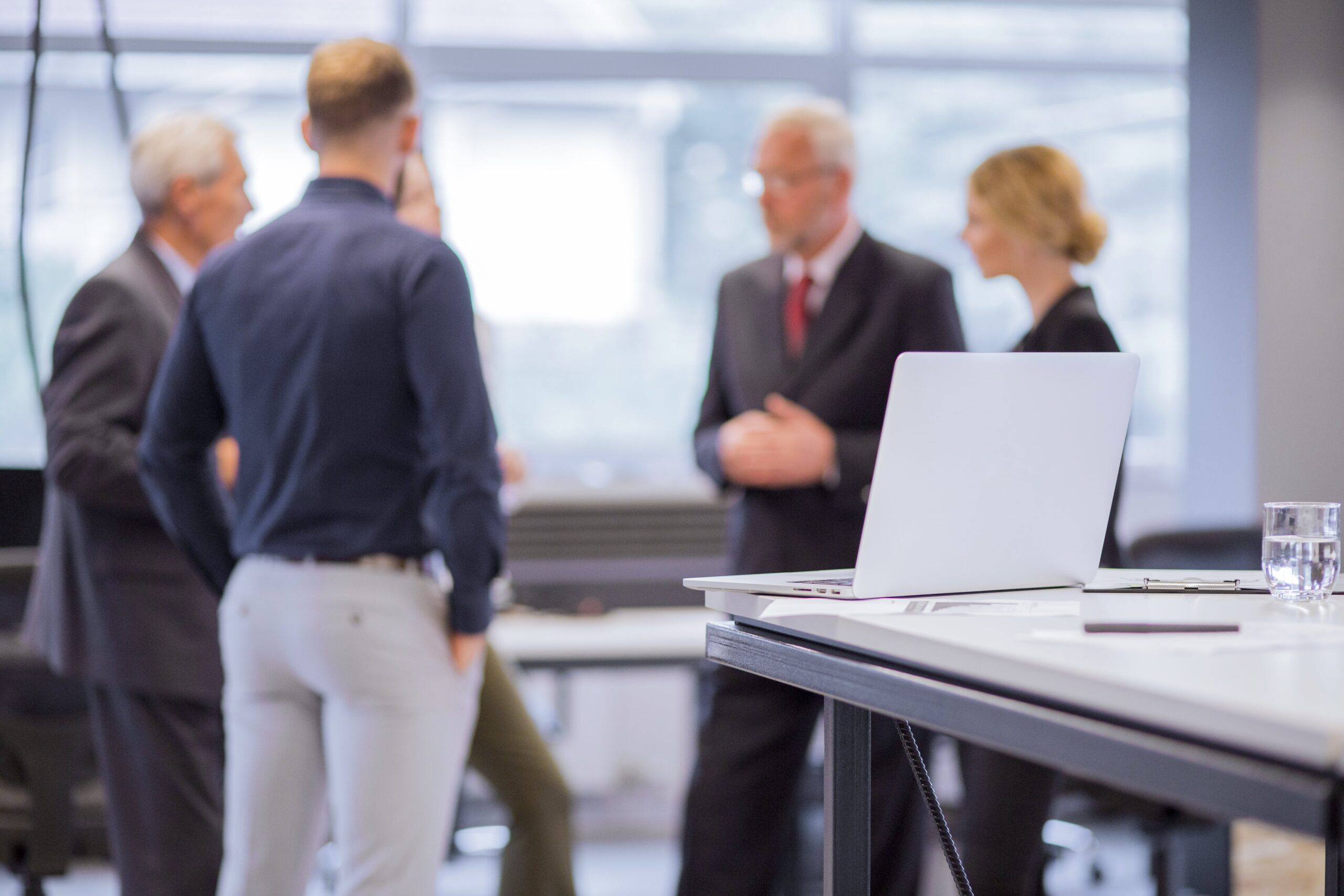 Group of business professionals standing confidently in front of a laptop on a table, representing teamwork, company formation, and legal consulting services in Egypt